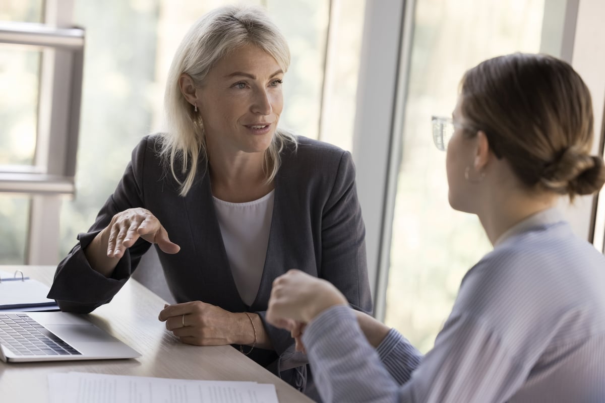 Two mature professional women talking at work table, discussing plans and growth