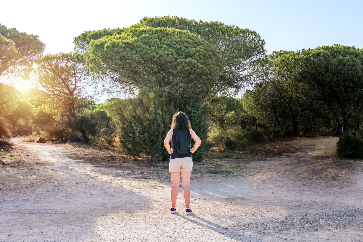 Woman choosing to take a light path or a dark path in a forest. Concept of decision making in life