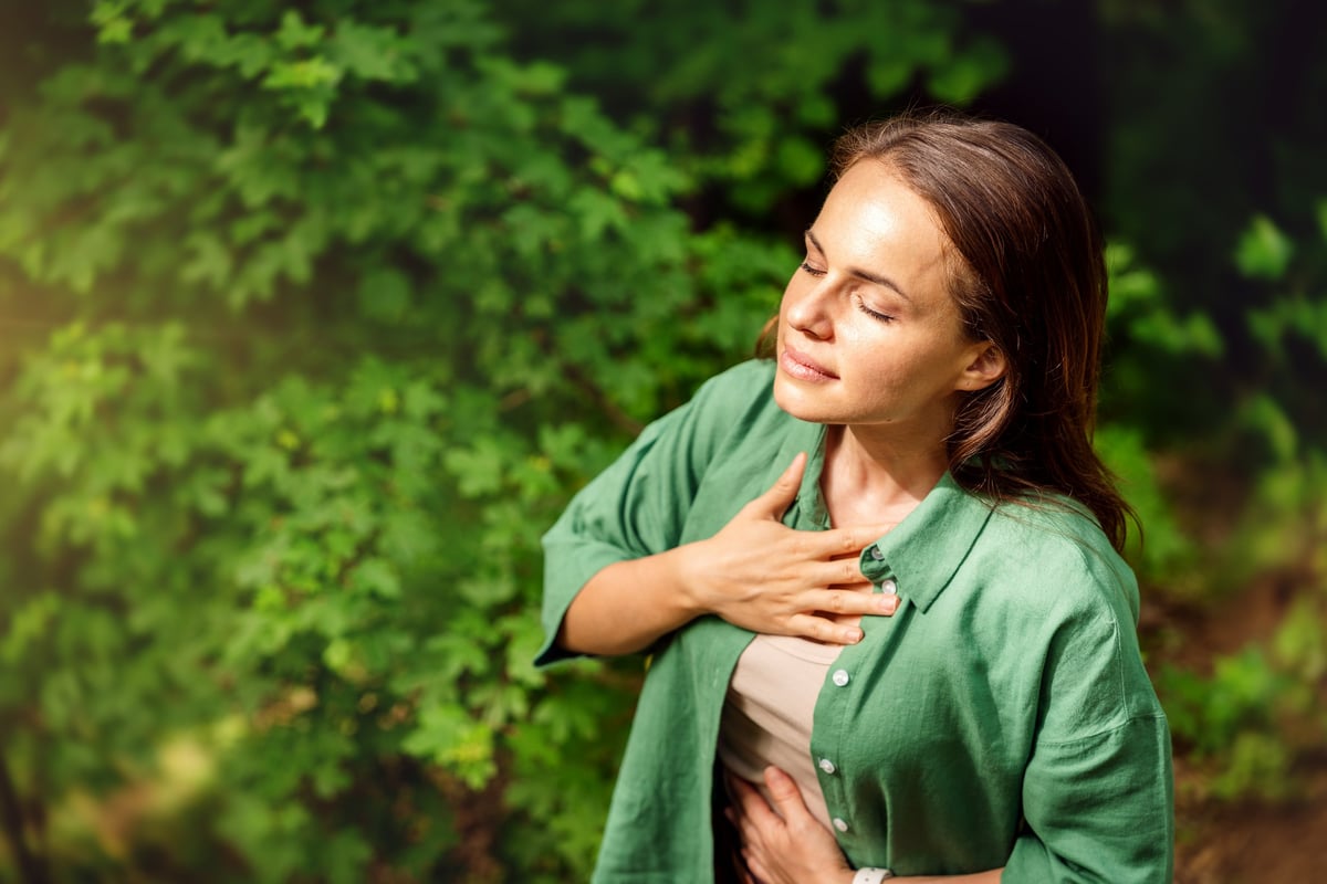 high angle view of young adult woman practising breathing exercise in the forest in summer
