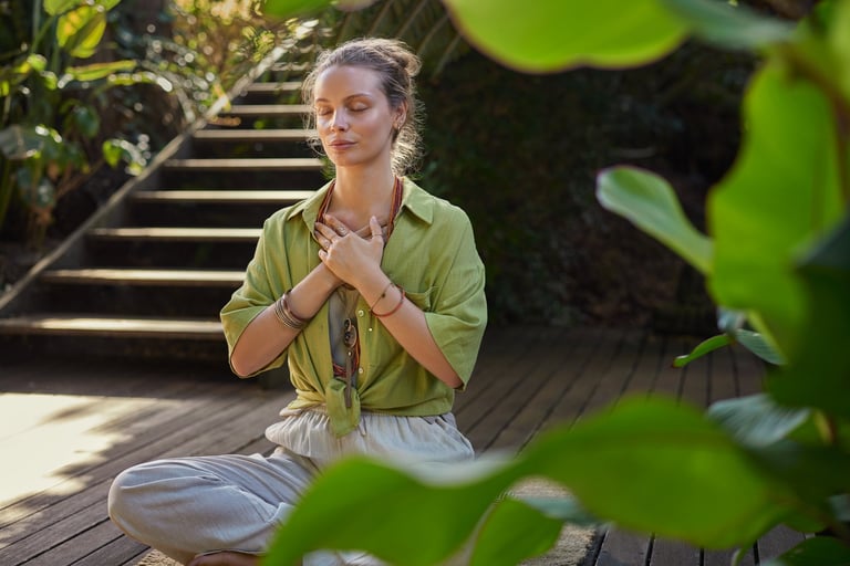 Peaceful woman sits cross-legged in a meditative state, hands over her heart, expressing gratitude and mindfulness