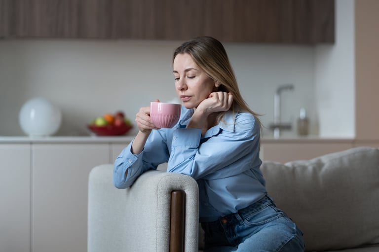 Self reflection with cup coffee of middle aged woman enjoying slowly calm time at home for stress relieve. Thoughtful mature female taking mindful pause rest on sofa pondering about simple pleasures.