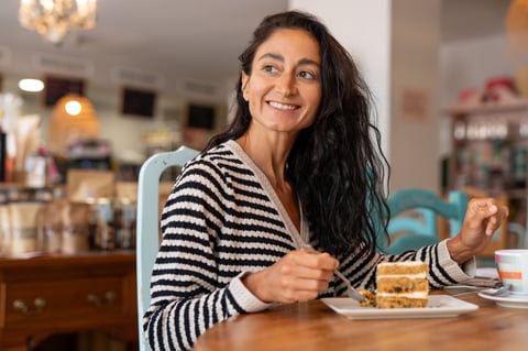 Mature woman sitting in cafe by window with coffee