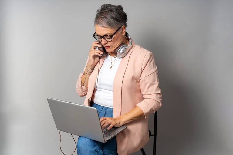 Mature businesswoman working from home, multitasking with a laptop and phone, demonstrating focus and efficiency in her home office