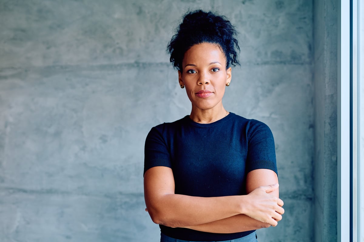 Professional businesswoman standing with a determined expression, embodying strength, leadership, and success in a modern workspace